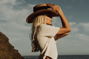 Girl posing in the beach with the "Isla Bonita" hat in tan color