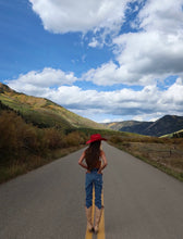 Load image into Gallery viewer, Girl wearing a western red hat in the middle of the road 
