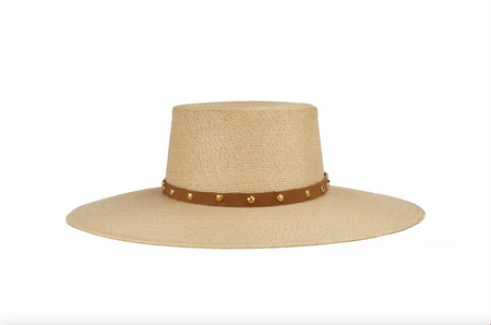 A light beige woven straw hat with a wide brim and a brown leather band decorated with small gold studs, shown against a plain white background.