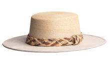 Load image into Gallery viewer, Straw hat in natural color made with palm leaves and the brim is made of structured suede finished with a combination braided trim, left side view
