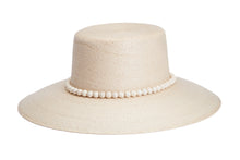Load image into Gallery viewer, A light beige woven straw hat with a wide brim and a decorative band of white faux pearls around the crown, shown on a solid white background. side
