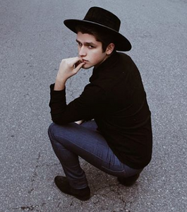 Boy posing in the street with a hat swathed in rich black velour fabric